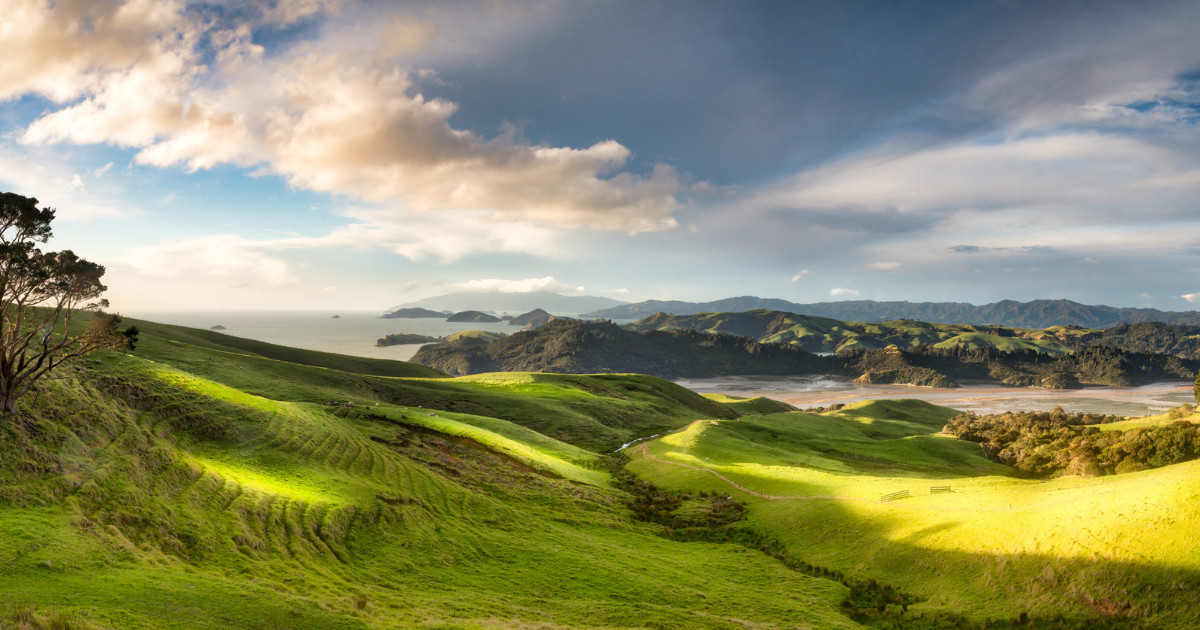 Green hills above an estuary, under a cloudy sky